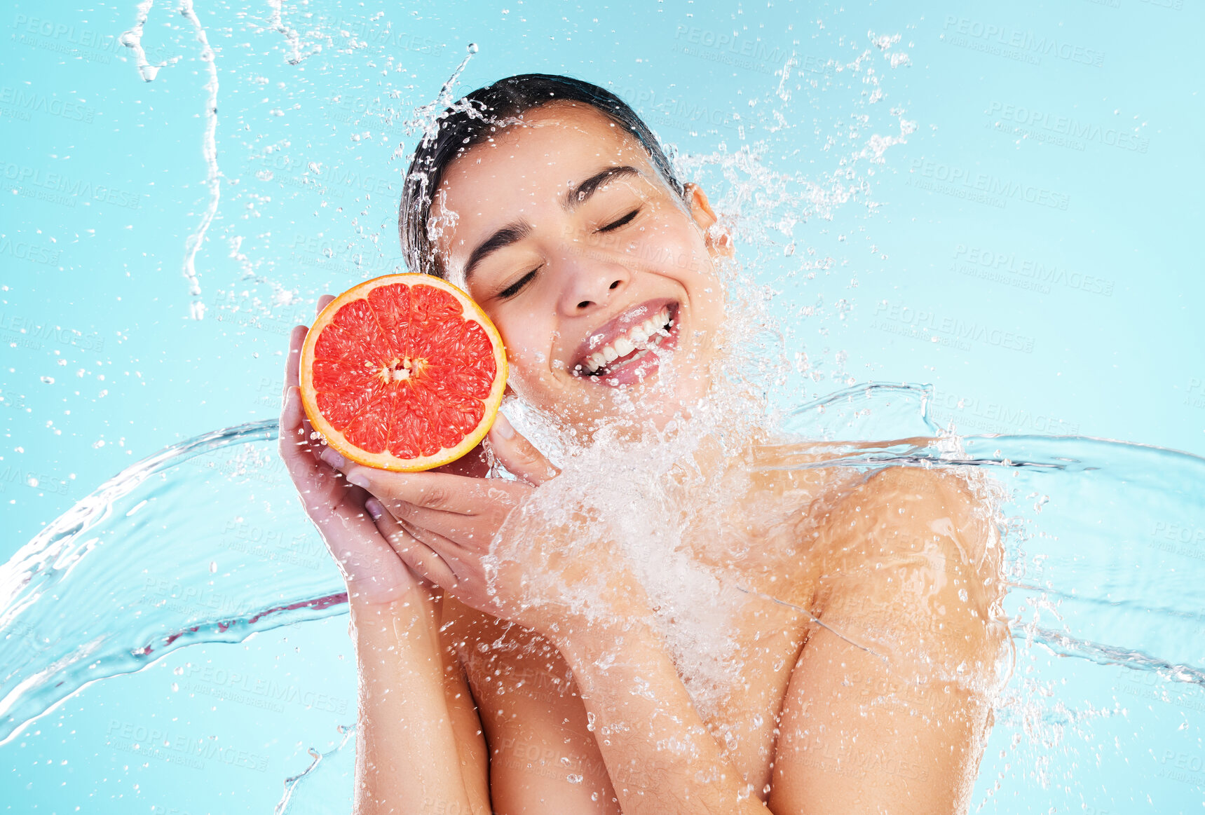 Buy stock photo Girl, water splash and grapefruit in studio, happy and diet with eyes closed by blue background. Woman, model and person with fruit, nutrition and benefits for detox with vegan food for self care