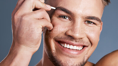 Buy stock photo Studio shot of a handsome young man plucking his eyebrows against a grey background