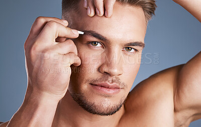 Buy stock photo Studio shot of a handsome young man plucking his eyebrows against a grey background