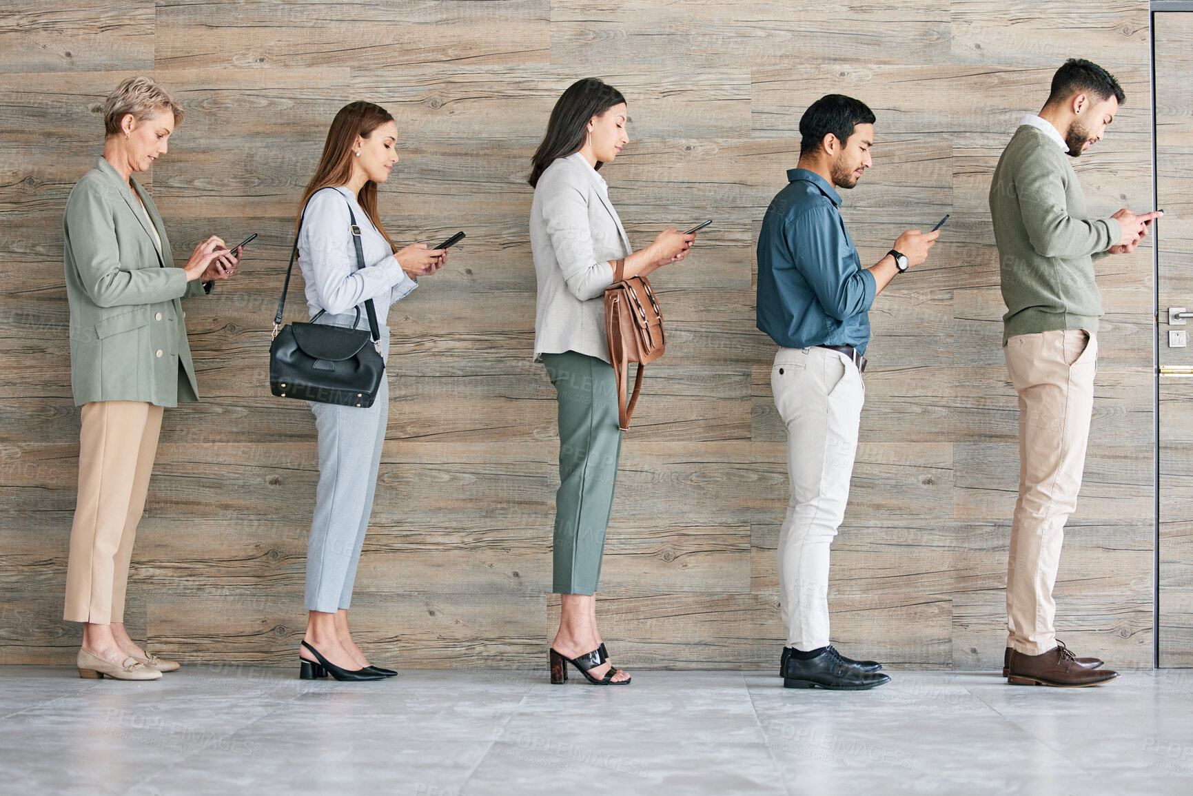 Buy stock photo Full length shot of a diverse group of businesspeople standing in a line together and using their cellphones