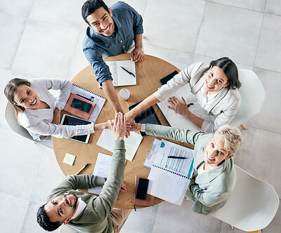Buy stock photo High angle shot of a group of young businesspeople joining hands in solidarity in a modern office
