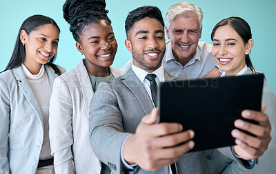Buy stock photo Studio shot of a diverse group of corporate businesspeople using a tablet to take selfies against a blue background