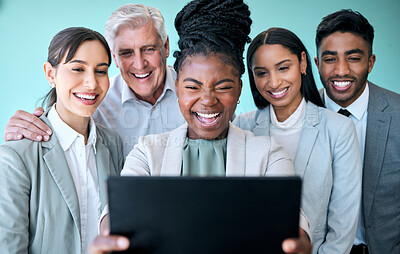 Buy stock photo Studio shot of a diverse group of corporate businesspeople using a tablet to take selfies against a blue background