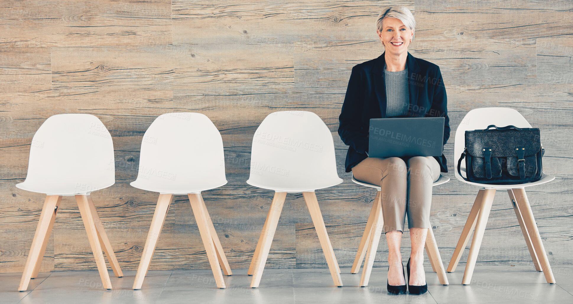 Buy stock photo Shot of a mature businesswoman using a laptop while waiting in line at an office