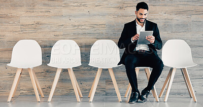 Buy stock photo Shot of a young businessman sitting  and using a tablet in an office