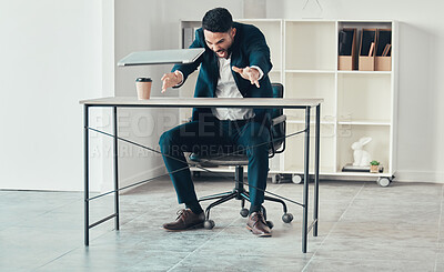 Buy stock photo Full length shot of a handsome young businessman sitting alone in the office and throwing his laptop in anger