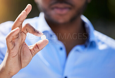 Buy stock photo Shot of an unrecognizable person holding a pill outside