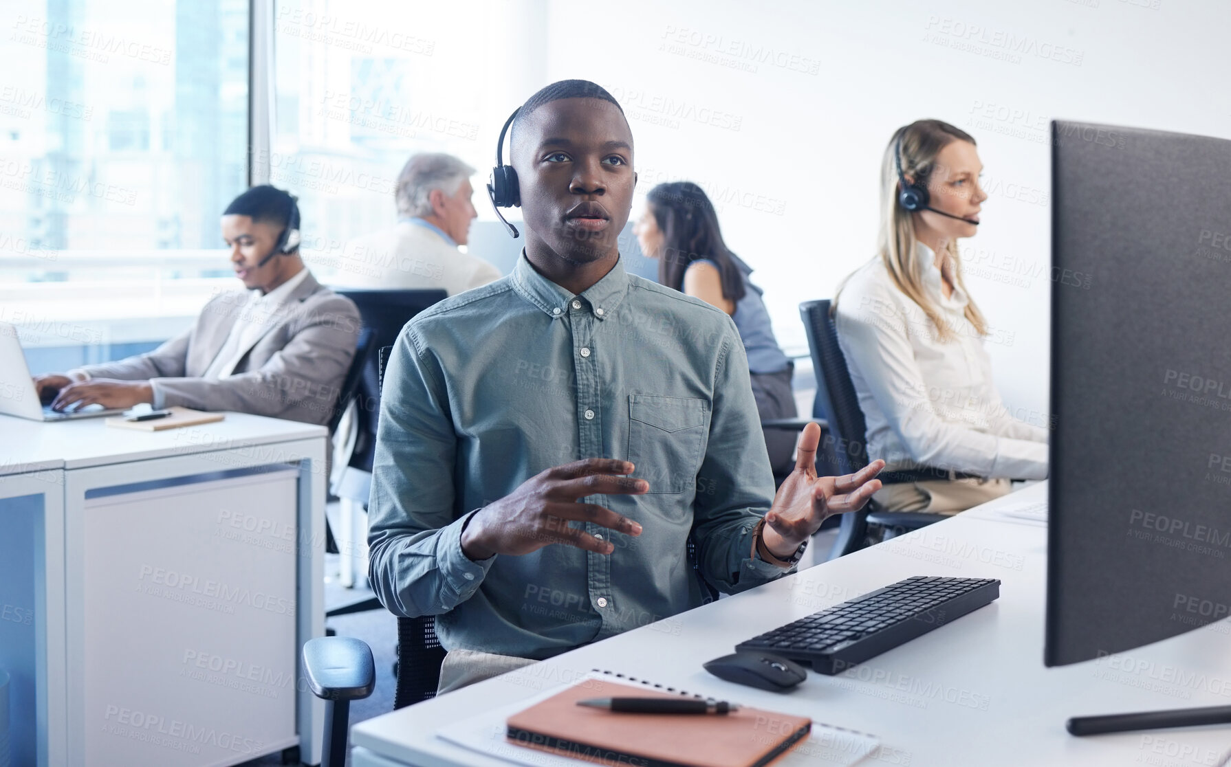 Buy stock photo Portrait of a young businessman using a headset and computer in a modern office