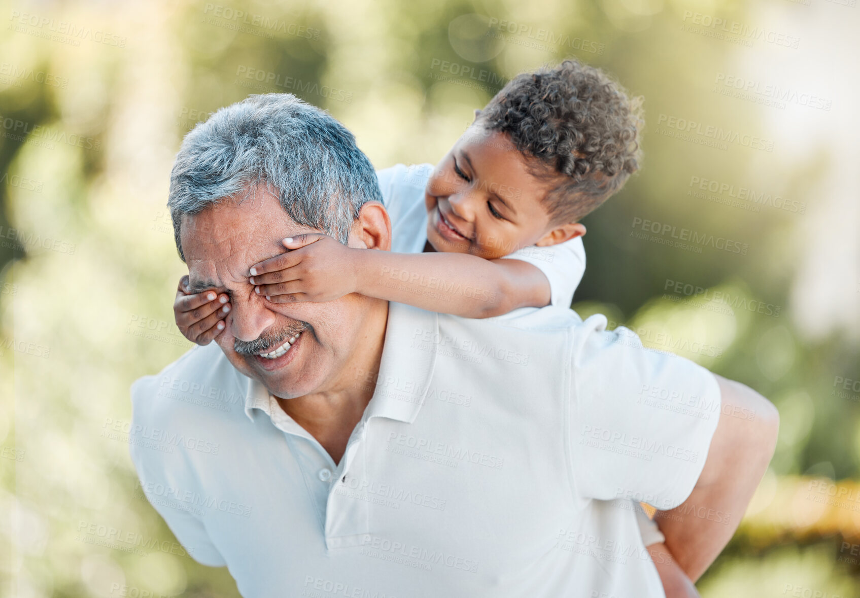 Buy stock photo Shot of a little boy covering his grandfather's eyes while playing outside