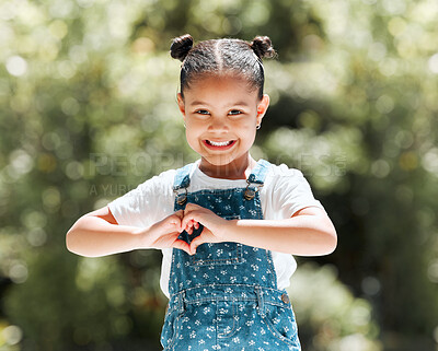 Buy stock photo Shot of a little girl forming a heart shape with her hands while standing outside
