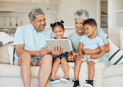 Buy stock photo Shot of grandparents bonding with their grandchildren and using a digital tablet on a sofa at home