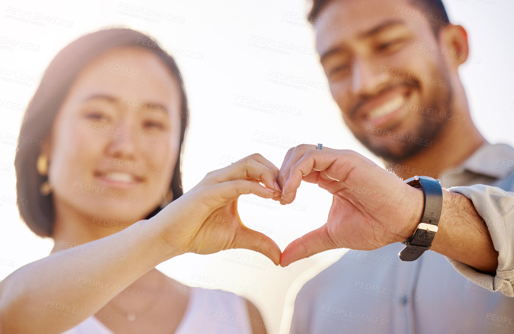 Buy stock photo Cropped shot of an affectionate young couple making a heart shape with their hands on the beach