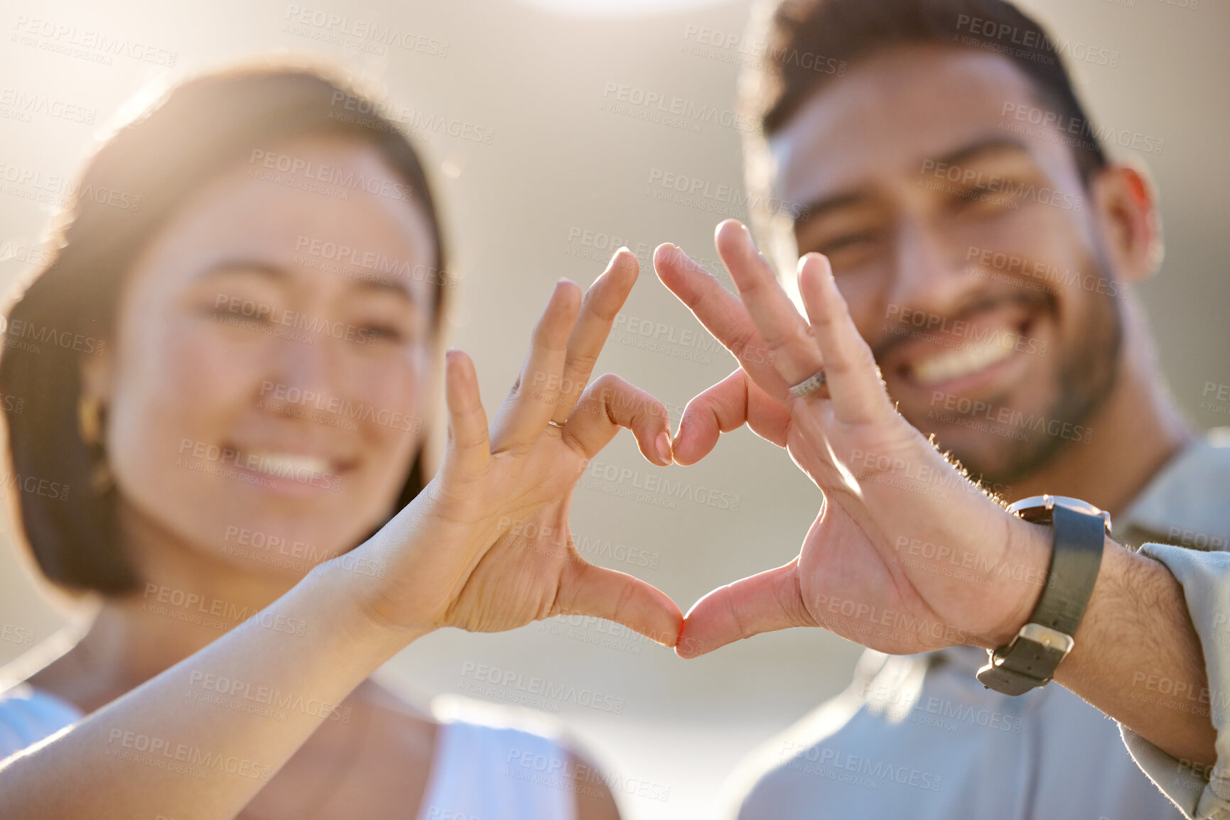 Buy stock photo Cropped shot of an affectionate young couple making a heart shape with their hands on the beach