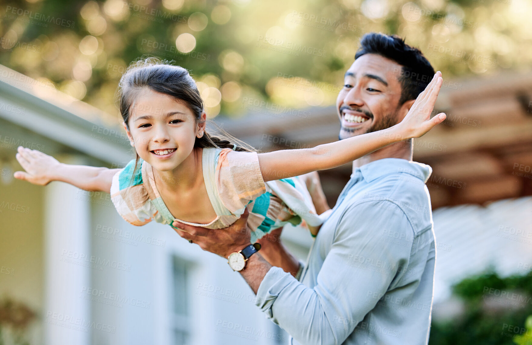 Buy stock photo Shot of a young father holding up his daughter in the garden outside