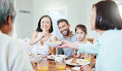 Buy stock photo Shot of a young couple have some lunch with the family at home