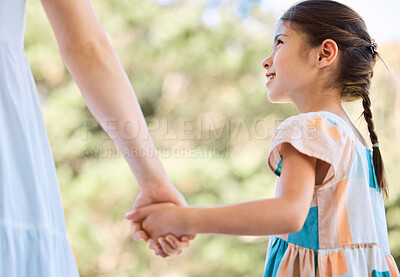 Buy stock photo Shot of an adorable little girl and her mother holding hands in a garden
