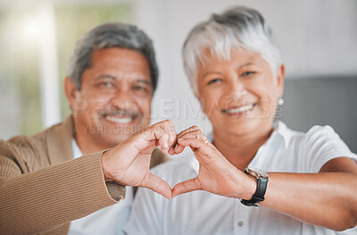 Buy stock photo Portrait of a senior couple making a heart shape with their hands at home