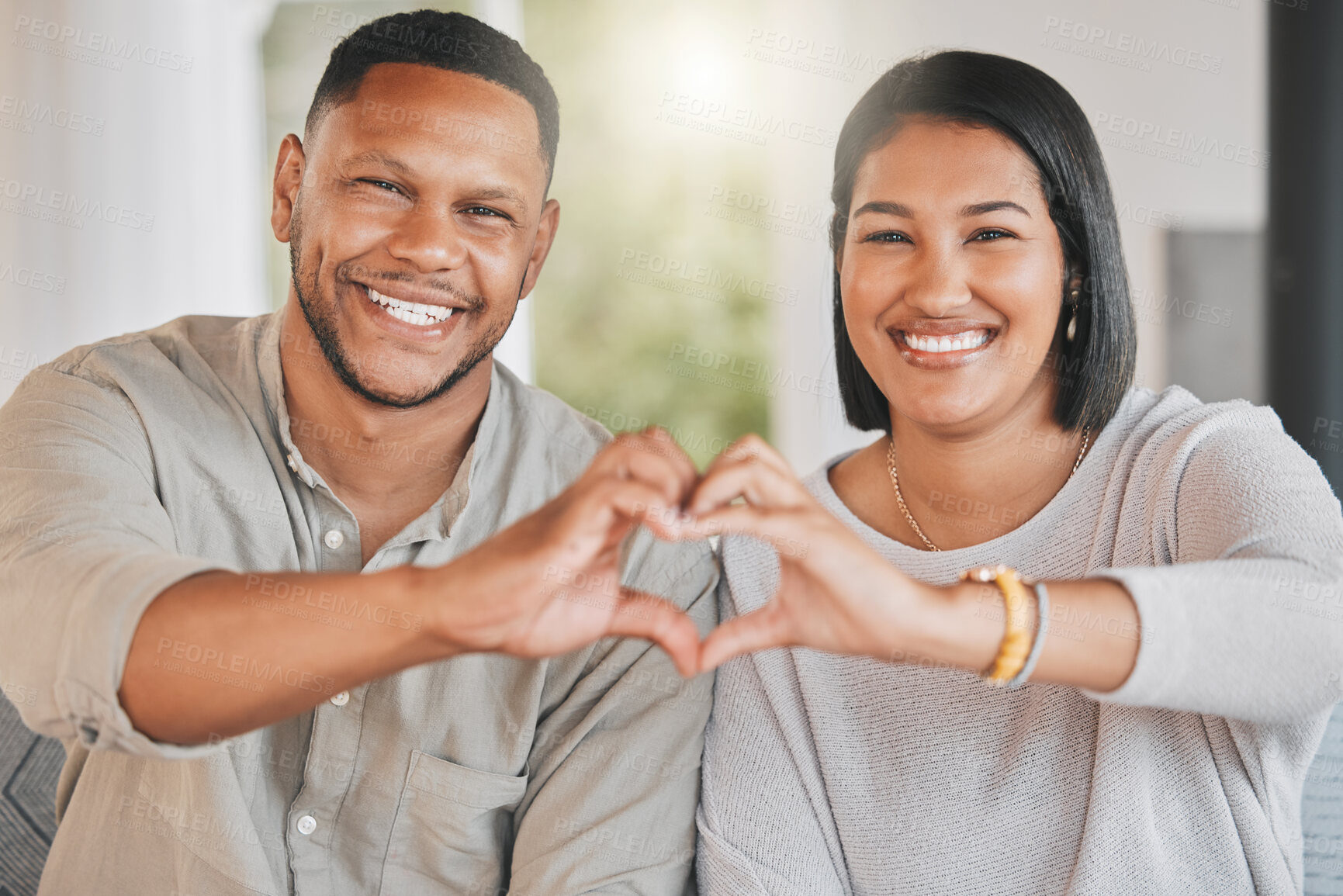 Buy stock photo Portrait of a young couple making a heart shape with their hands at home