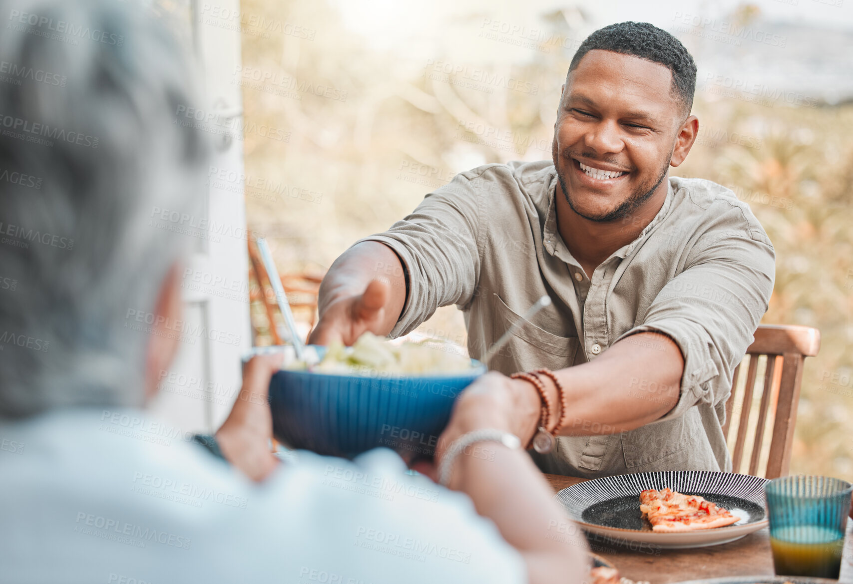 Buy stock photo Man, woman and outdoor lunch with sharing, happy bonding and food on terrace at home. Pizza, salad and family at picnic table together with smile, care and love on patio for weekend in backyard