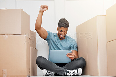 Buy stock photo Full length shot of a young man sitting in his new home and celebrating a success while using his laptop