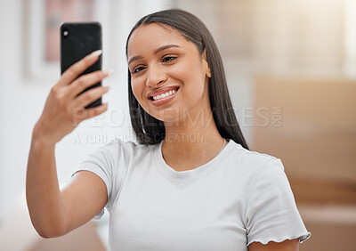Buy stock photo Shot of an attractive young woman using her cellphone to take a selfie in her new home