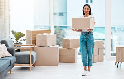 Buy stock photo Full length shot of an attractive young woman standing alone in her new home and holding a box