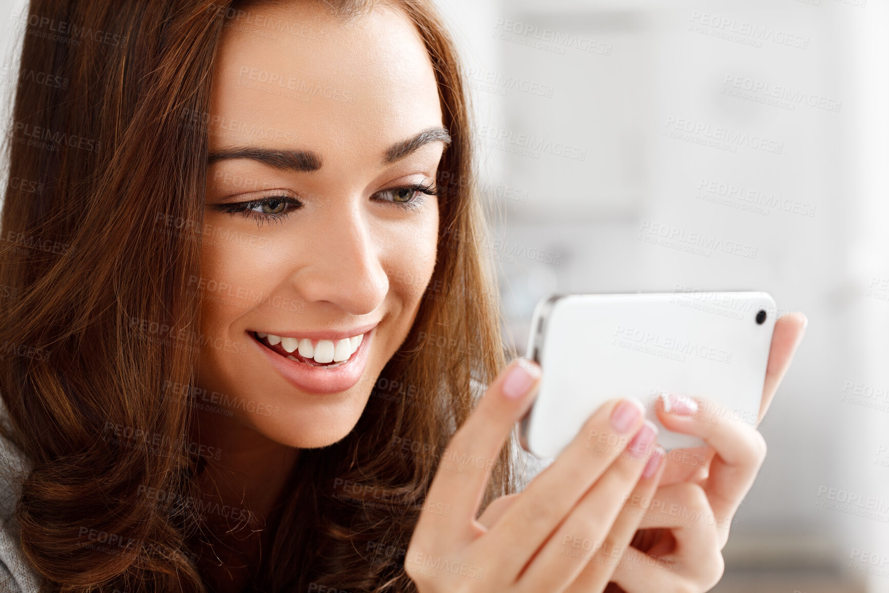 Buy stock photo Happy woman watching videos with a phone with an internet app online to stream or download. Young lady smiling while reading a funny meme or enjoying a web series or movie with a smartphone at home