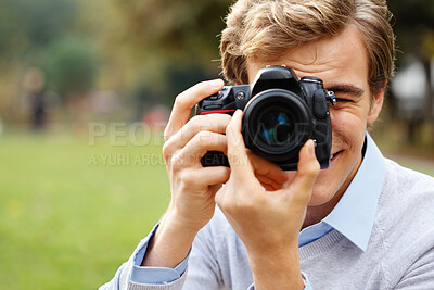 Buy stock photo Shot of a young man taking photos in a park