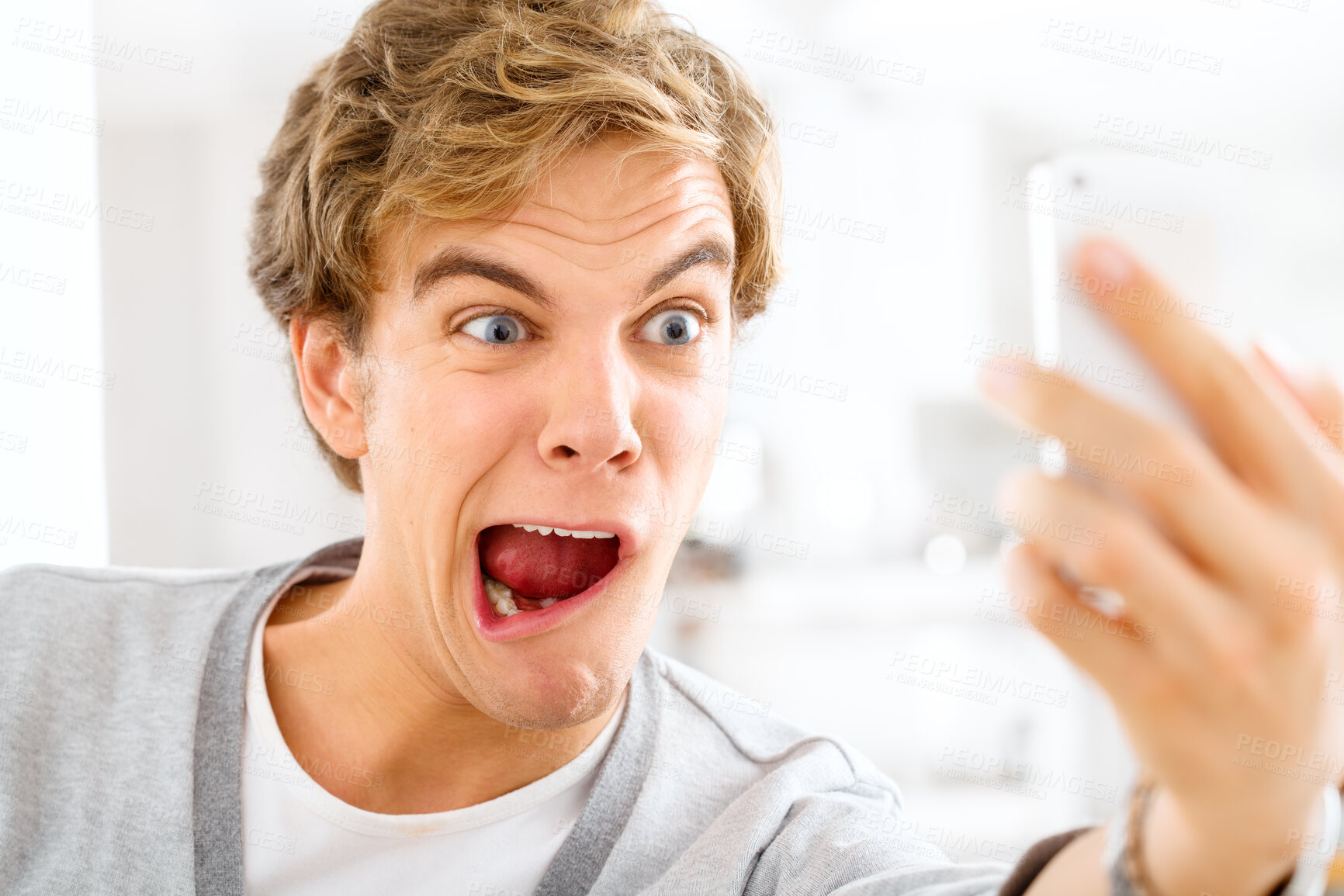 Buy stock photo Crazy, man and online selfie with funny post to social media, website or film silly video in home. Goofy, face and weird profile picture of gen z person in apartment with strange emoji or expression