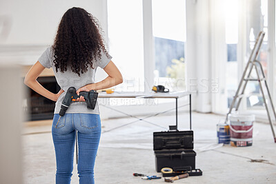 Buy stock photo Shot of a young woman holding a cordless drill while busy with renovations