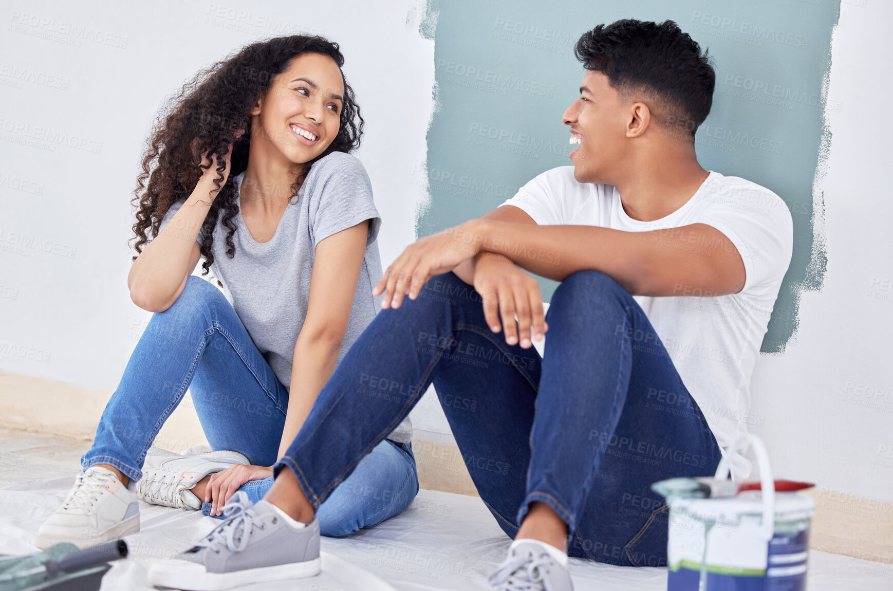 Buy stock photo Shot of a young couple painting a wall in a room together