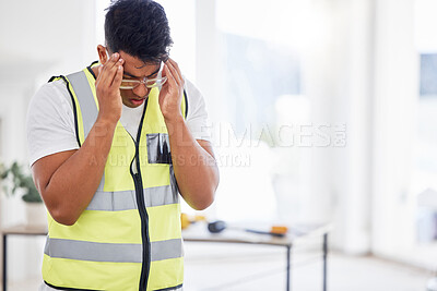 Buy stock photo Shot of a young contractor standing alone inside and suffering from a headache