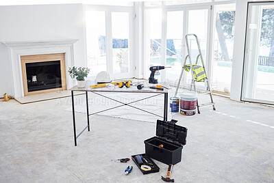 Buy stock photo Shot of building plans and equipment on a table in an empty living room during the day