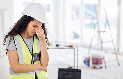Buy stock photo Shot of an attractive young contractor standing alone inside and suffering from a headache