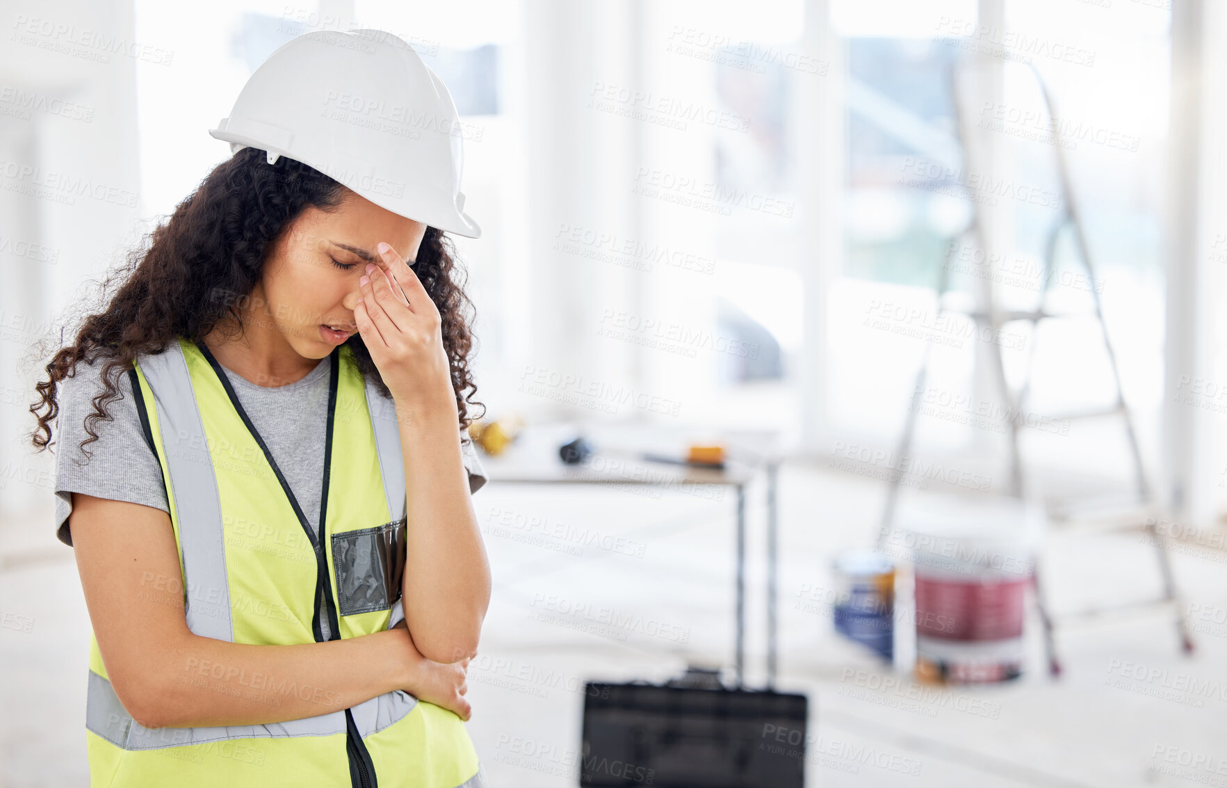 Buy stock photo Shot of an attractive young contractor standing alone inside and suffering from a headache