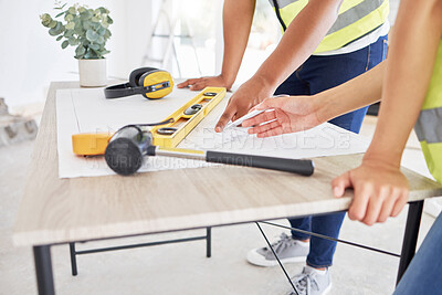 Buy stock photo Cropped shot of two unrecognisable contractors standing inside together and looking at building plans