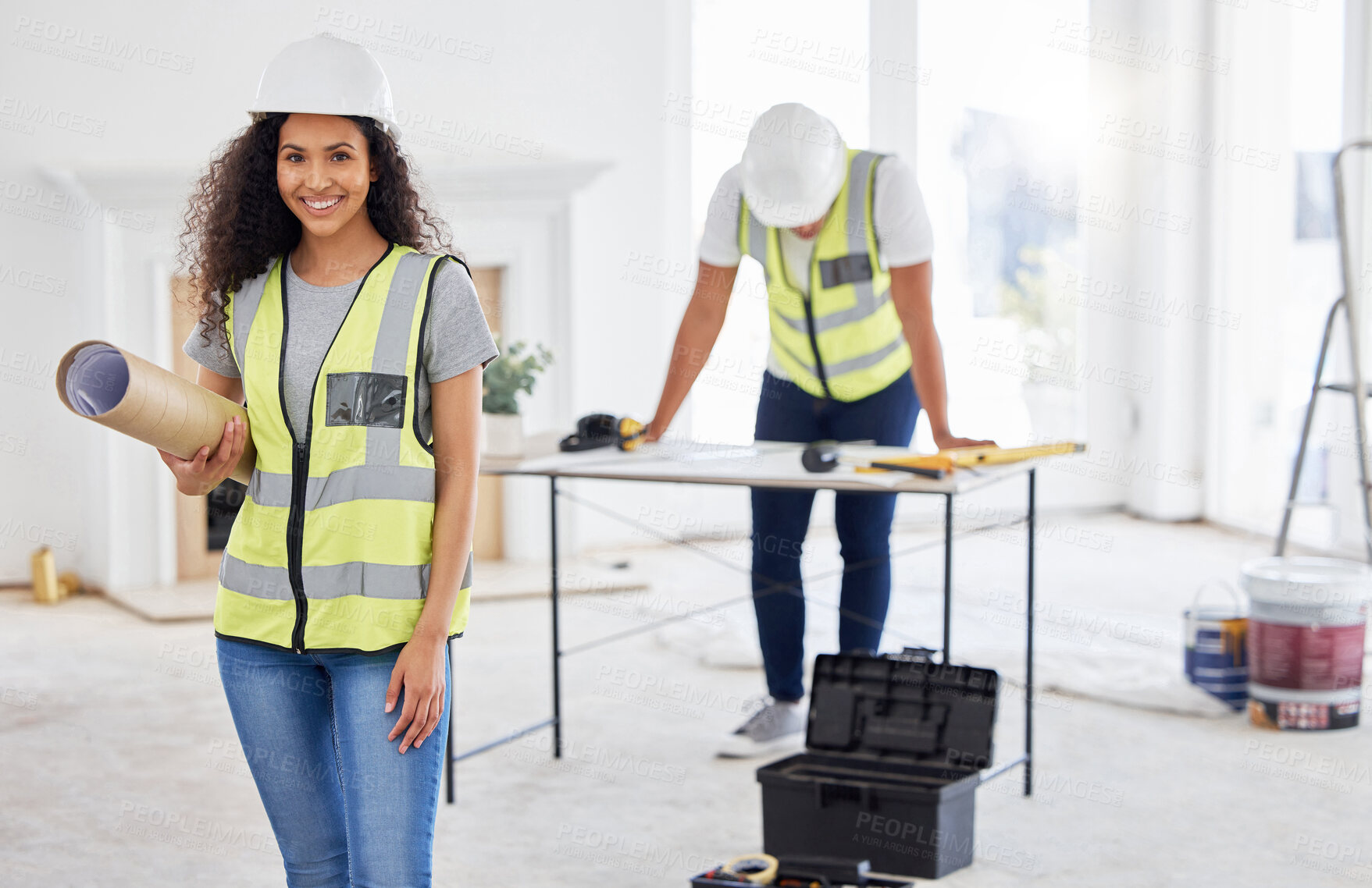 Buy stock photo Shot of an attractive young contractor standing inside and holding building plans