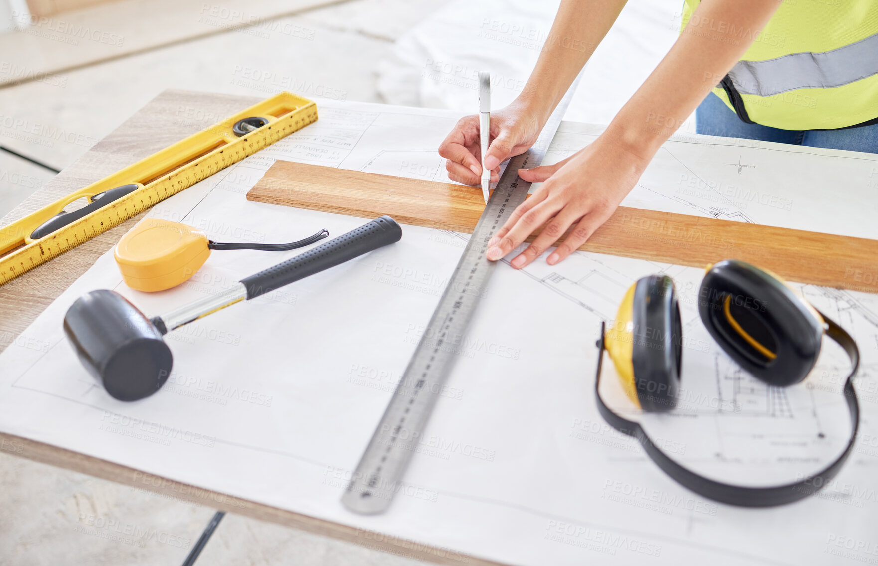 Buy stock photo Cropped shot of an unrecognisable contractor standing alone inside and using a ruler to draw up building plans