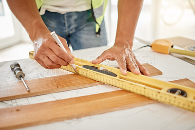Buy stock photo Cropped shot of an unrecognisable construction worker standing alone and using a ruler to measure a beam of wood