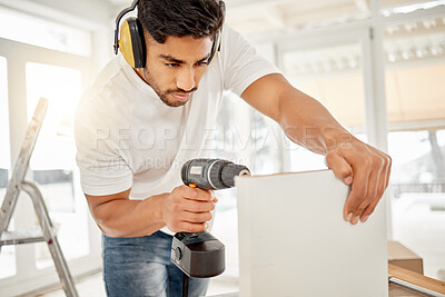 Buy stock photo Shot of a handsome young man standing alone in his home and using a power drill