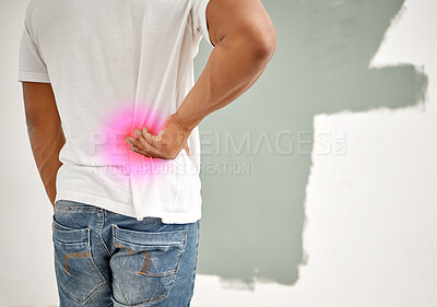 Buy stock photo Shot of a man experiencing back pain while busy painting at home