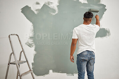 Buy stock photo Shot of a young man painting a wall at home