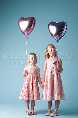 Buy stock photo Children, holding hands and sister with heart balloon in studio on blue background for family or party. Birthday, celebration event or happy with smile of girl kids on color backdrop together