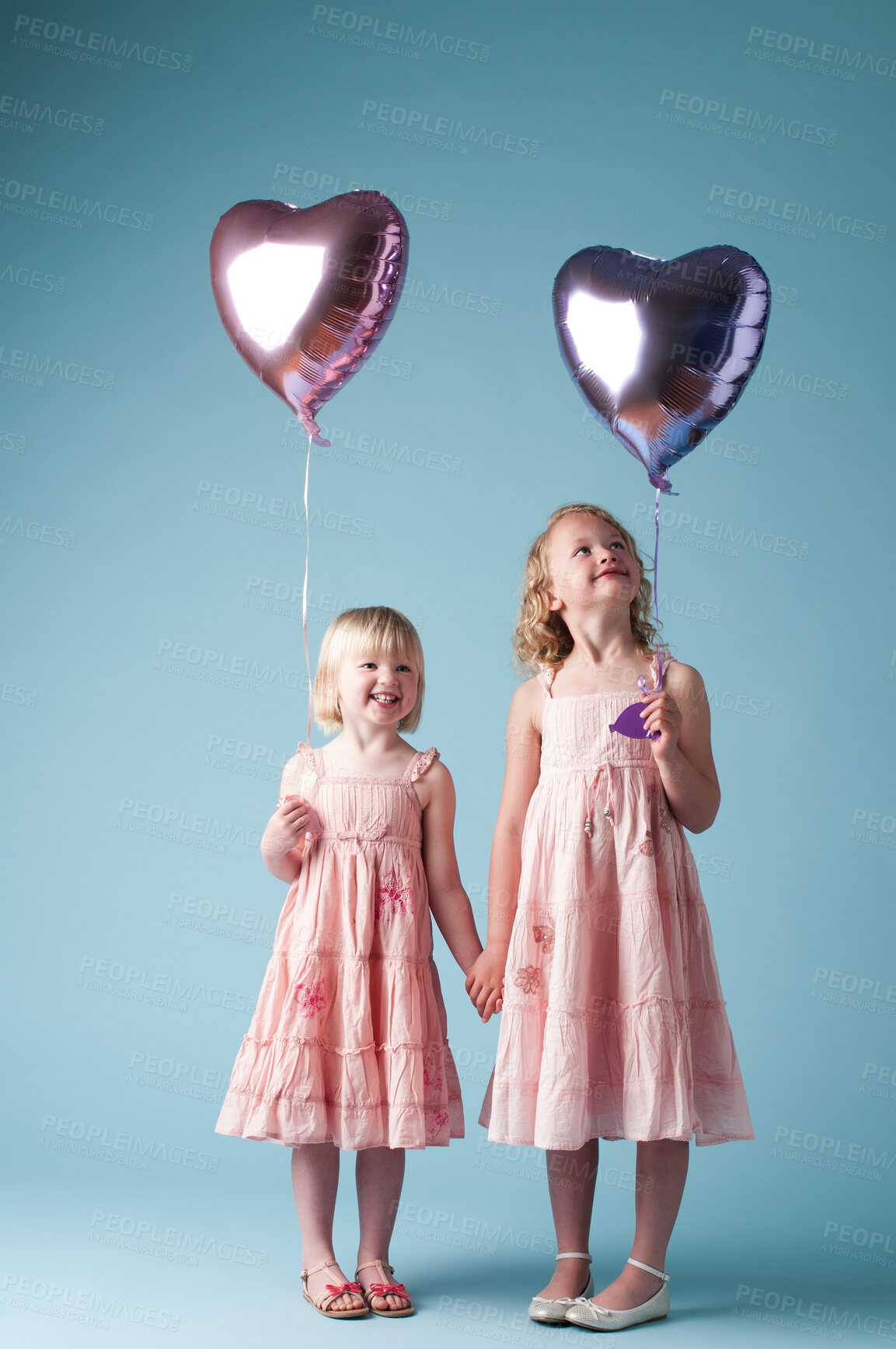 Buy stock photo Children, holding hands and sister with heart balloon in studio on blue background for family or party. Birthday, celebration event or happy with smile of girl kids on color backdrop together