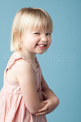 Buy stock photo Little girl, smile and playful in studio with portrait for child development on blue background. Sneaky, rascal and confident in childhood with youth for joy with fun, happy and innocent cute face