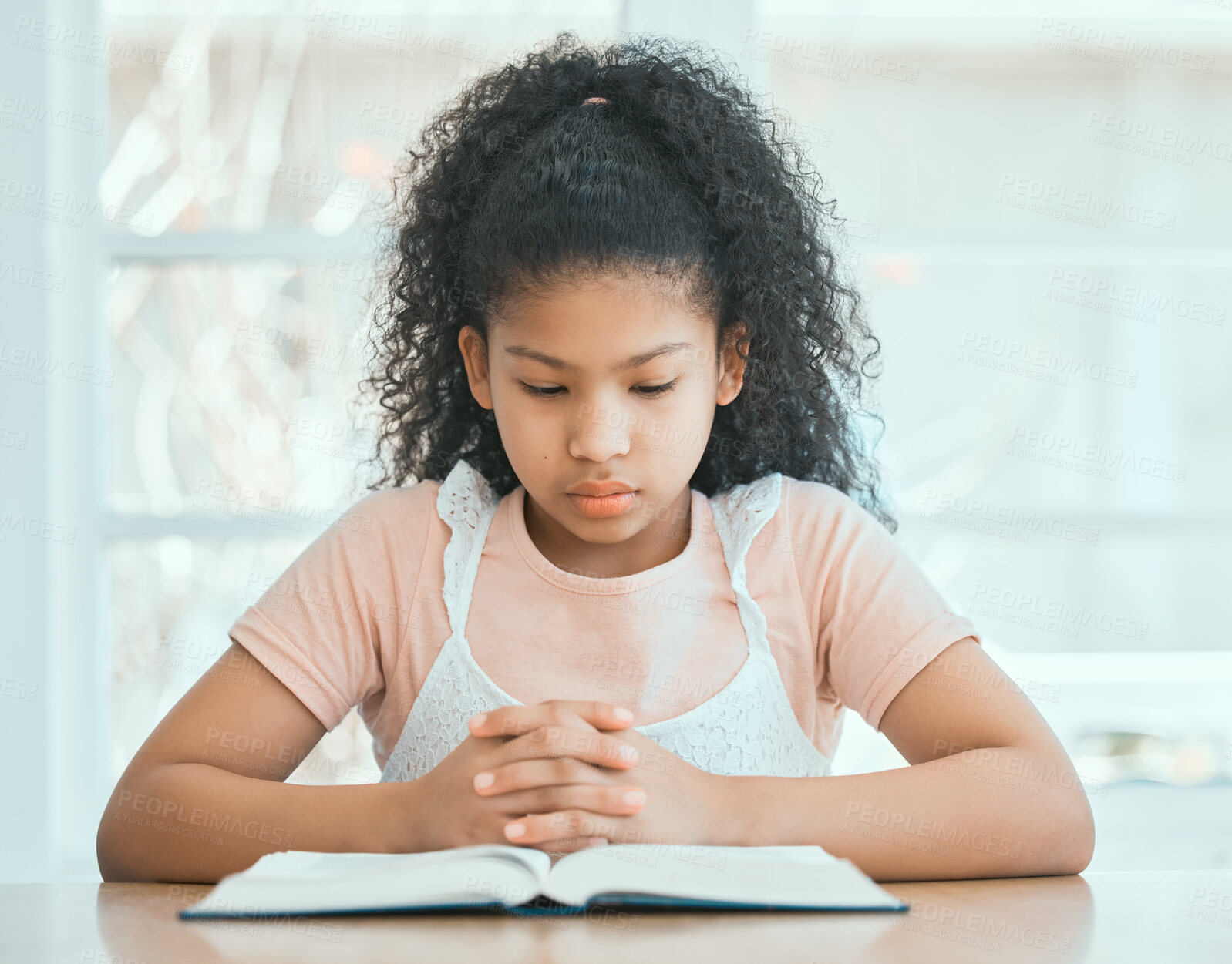 Buy stock photo Girl, reading and bible at table in home with worship, spiritual prayer and knowledge of Jesus Christ. Christian child, education and holy book for praise to God, forgiveness and thankful in lounge