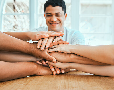 Buy stock photo Shot of a group of family members stacking their hands while sitting at the table at home
