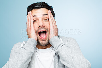 Buy stock photo Man, shocked or surprised in portrait with hands on face in blue studio background for excitement, wow and amazed. Male person, omg expression and alert isolated against backdrop for good news