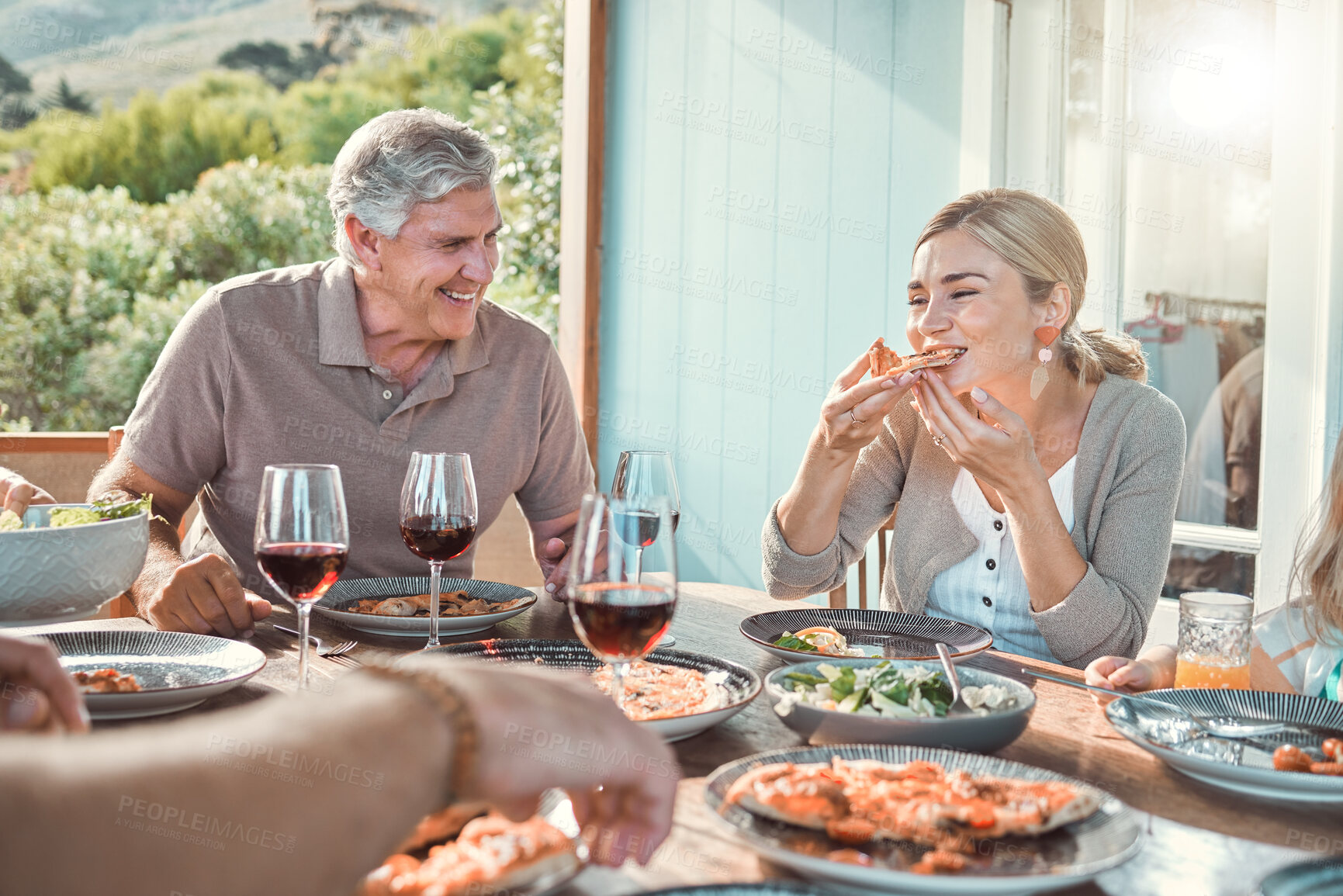 Buy stock photo Lunch, bonding and family with food, laughing and weekend gathering event at table on patio. Happy old man, woman and pizza in backyard eating together for fun dinner celebration on terrace at home