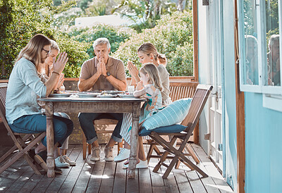 Buy stock photo Full length shot of a family sitting together and praying before lunch